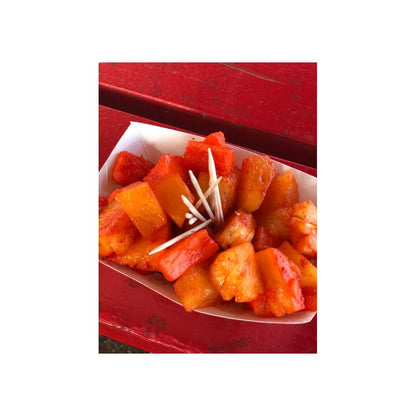 Cubed pineapple and papaya sprinkled with li hing mui powder served in a paper tray with toothpicks